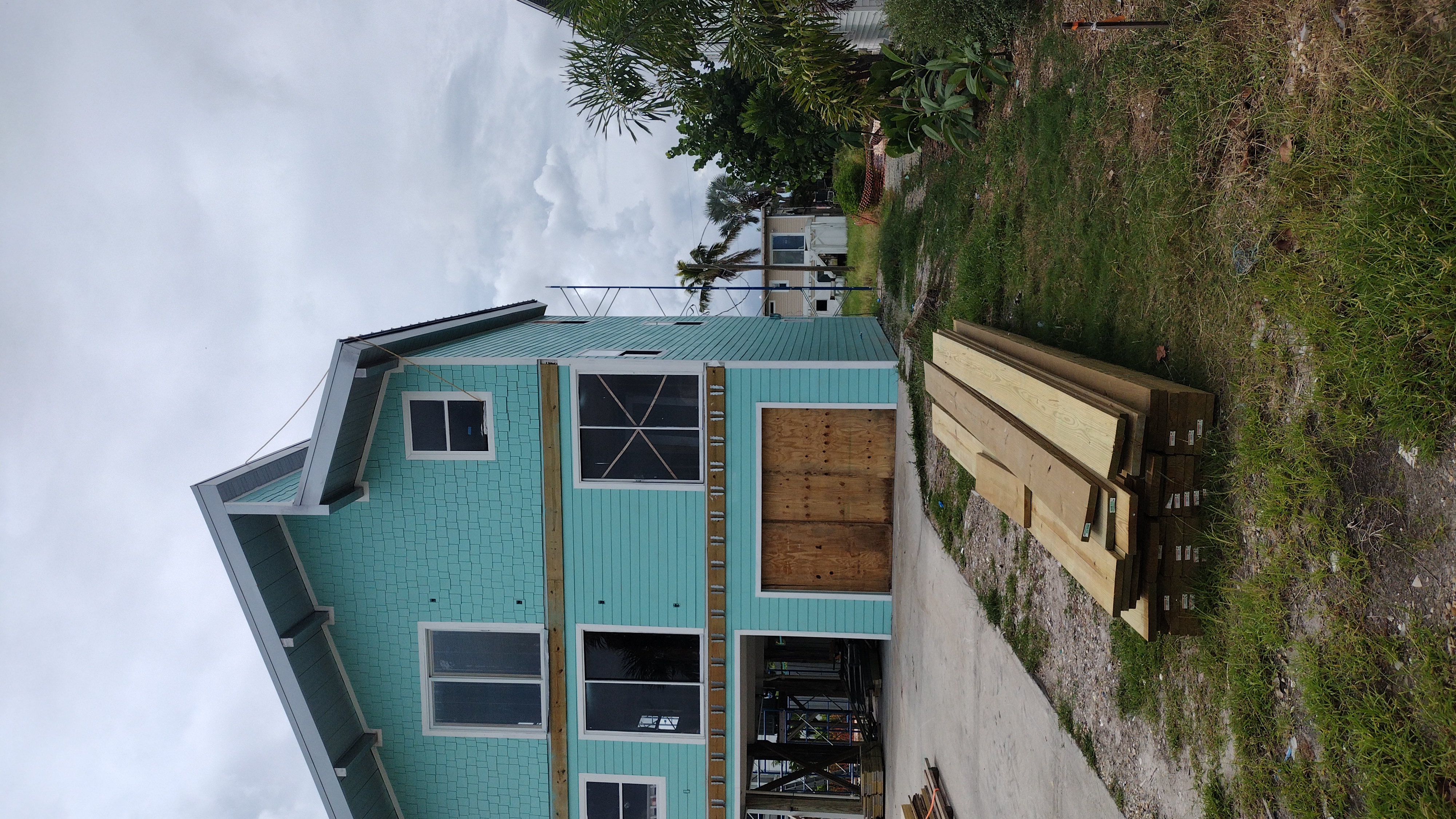 New two-tone James Hardie siding wrapping the home, materials staged on site — Bell Engineering & Construction
