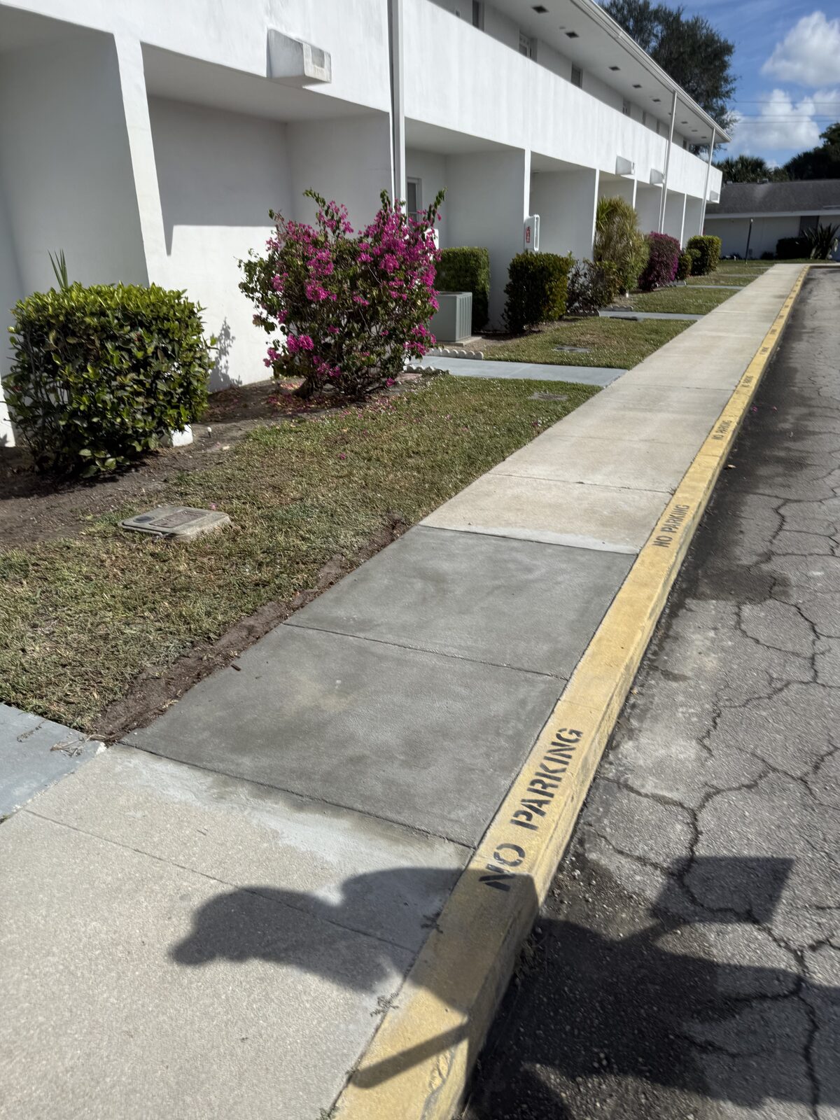 The completed sidewalk repair cured and back in service, blending into the continuous walkway running past the villa buildings