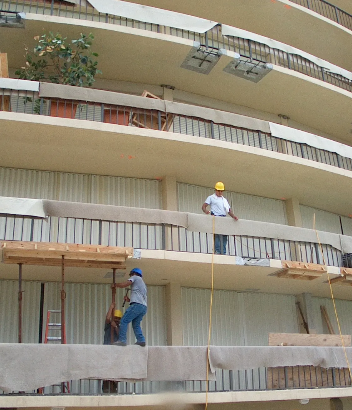 Workers setting shoring beneath the curved balcony slabs of North Ocean One during its concrete restoration