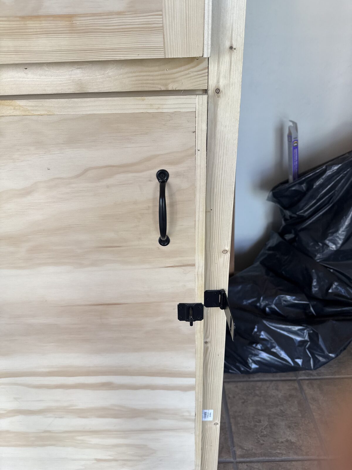 Site-built locker doors in raw pine with black pulls and hasp hardware before paint — Bell Engineering & Construction