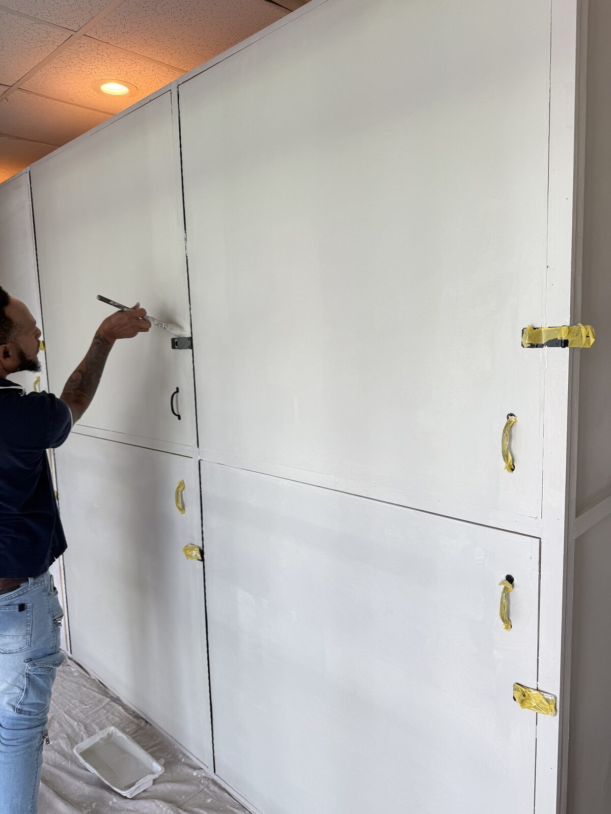 Painting the new locker bank with the pulls and hasps masked off in tape — Bell Engineering & Construction