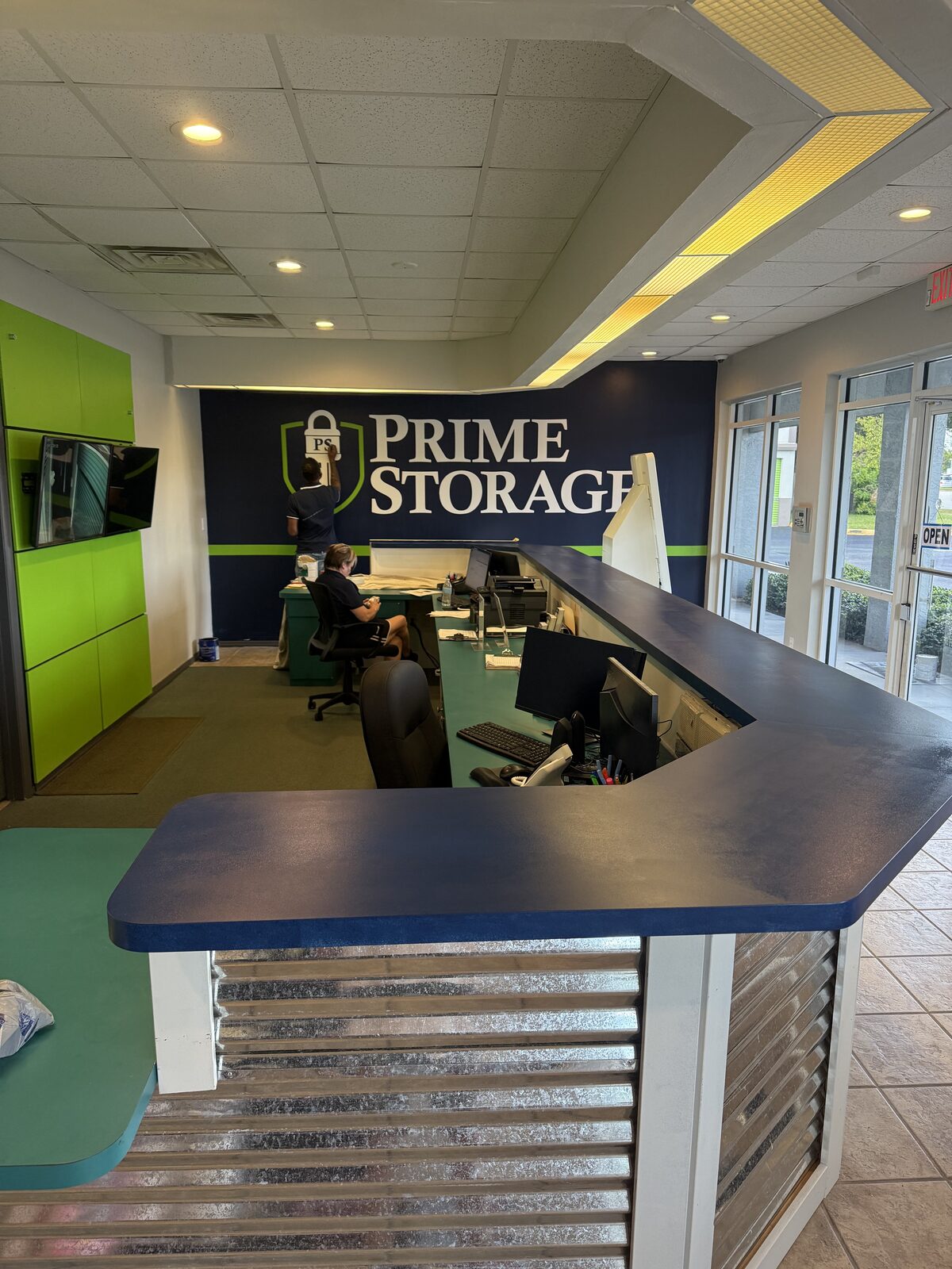 Rebuilt front counter with navy laminate top and corrugated galvanized cladding, staff working behind it — Bell Engineering & Construction
