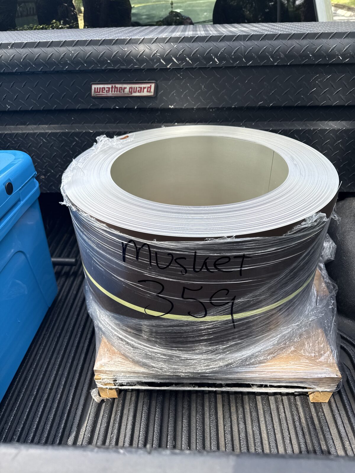 Roll of musket brown aluminum gutter coil stock strapped to a pallet in a pickup truck bed, Royal Palm Beach FL