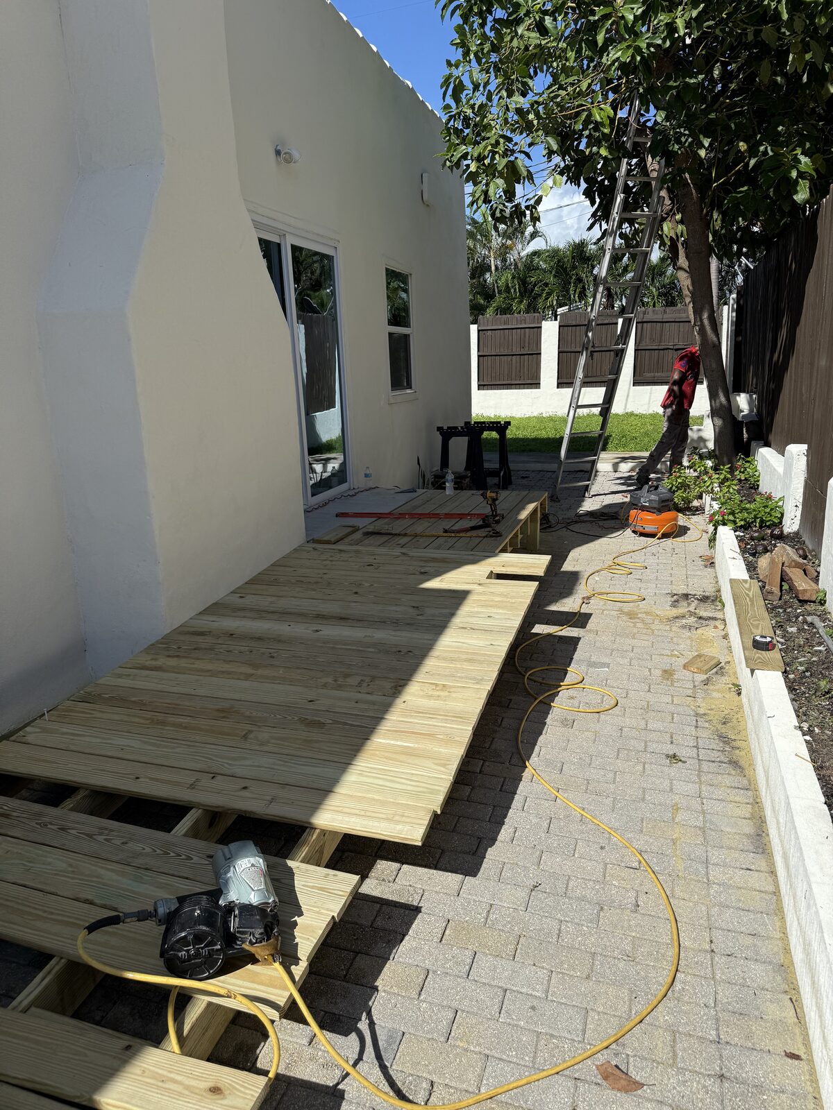 Ramp decking most of the way on, running from the paver patio up toward the sliding-door landing along the side of the house