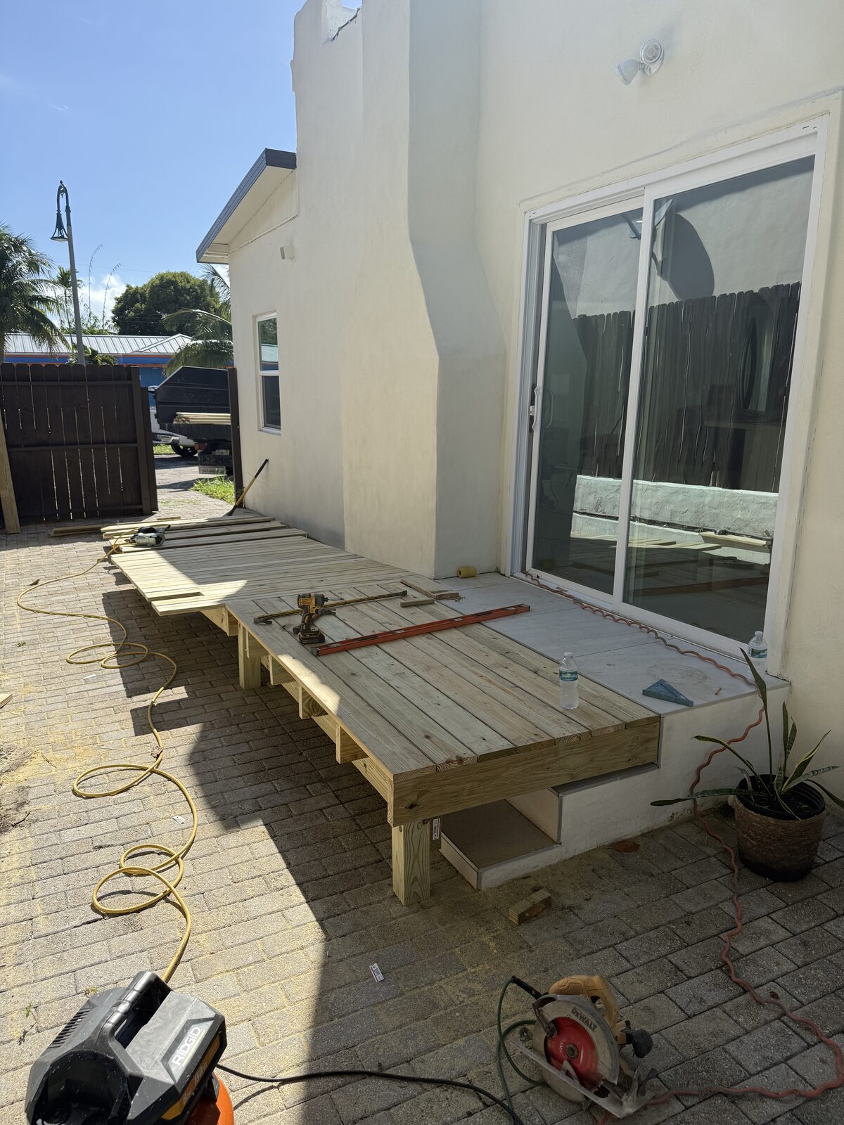 Level and long straightedge laid across the new timber landing at the sliding-glass door to check it against the existing tiled threshold