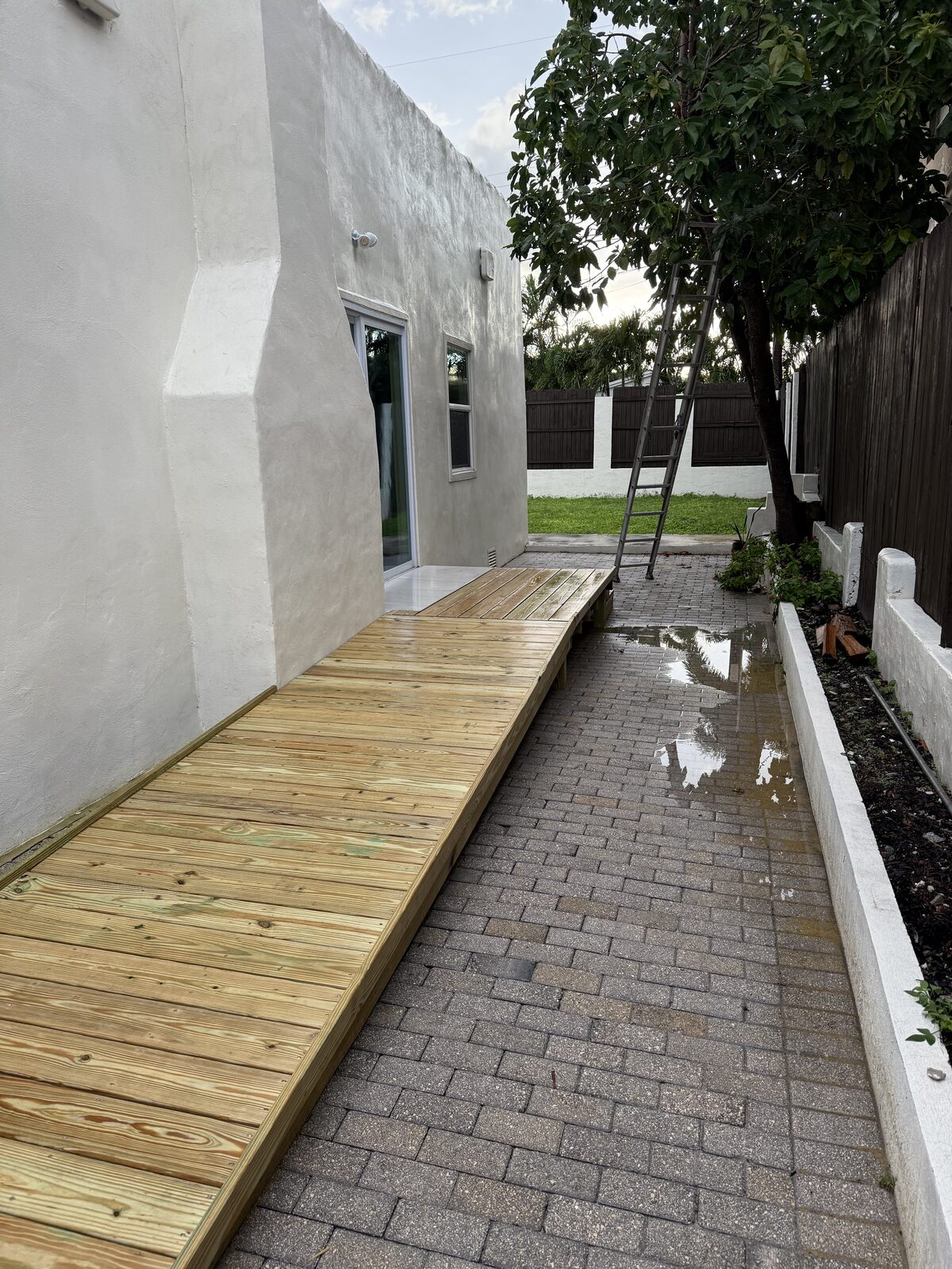 View up the finished ramp from the low end, showing a gentle continuous slope rising the length of the side yard to the door landing