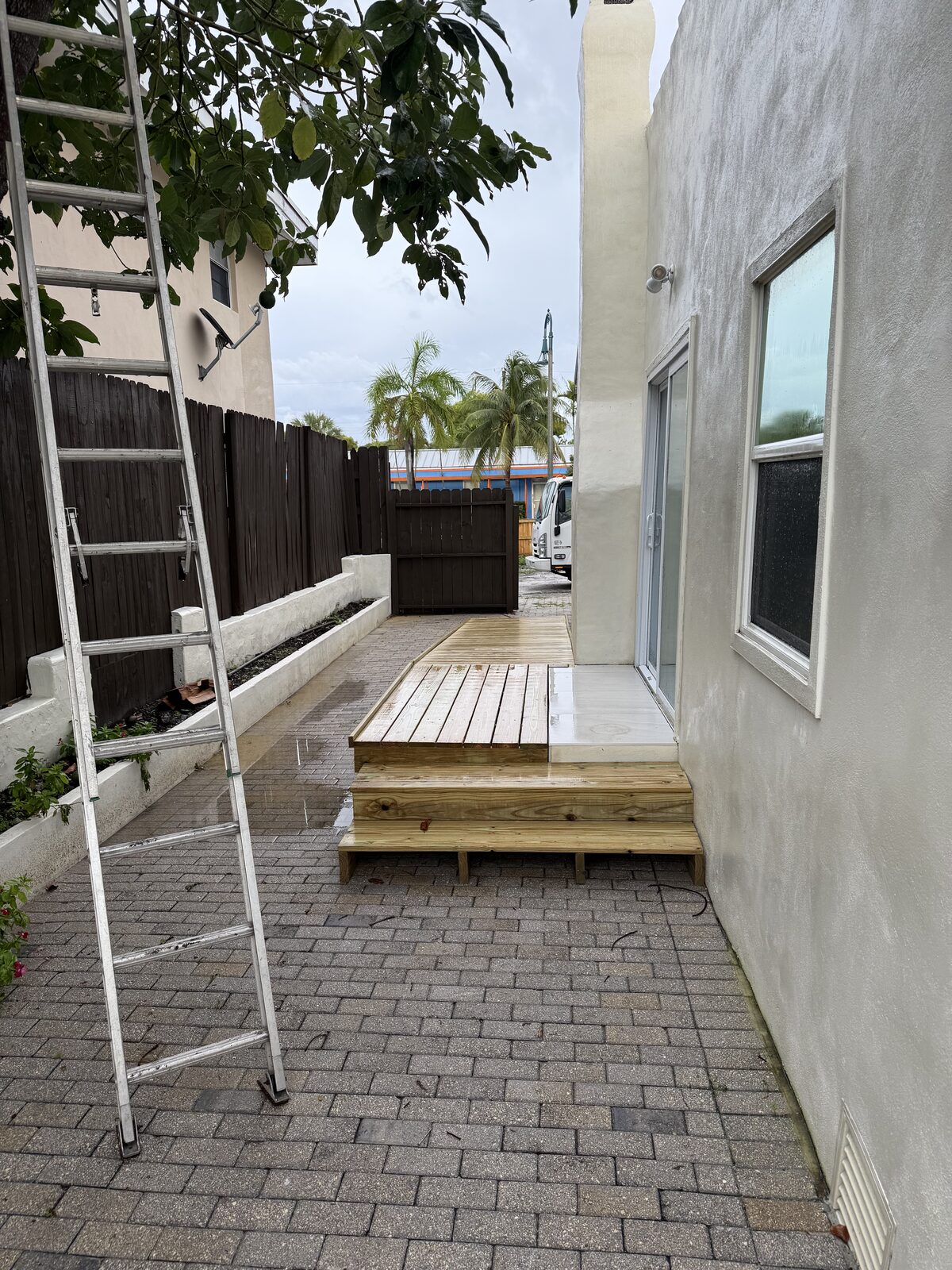 Finished ramp, landing and steps in the side yard with the ramp continuing out toward the open gate and the driveway beyond