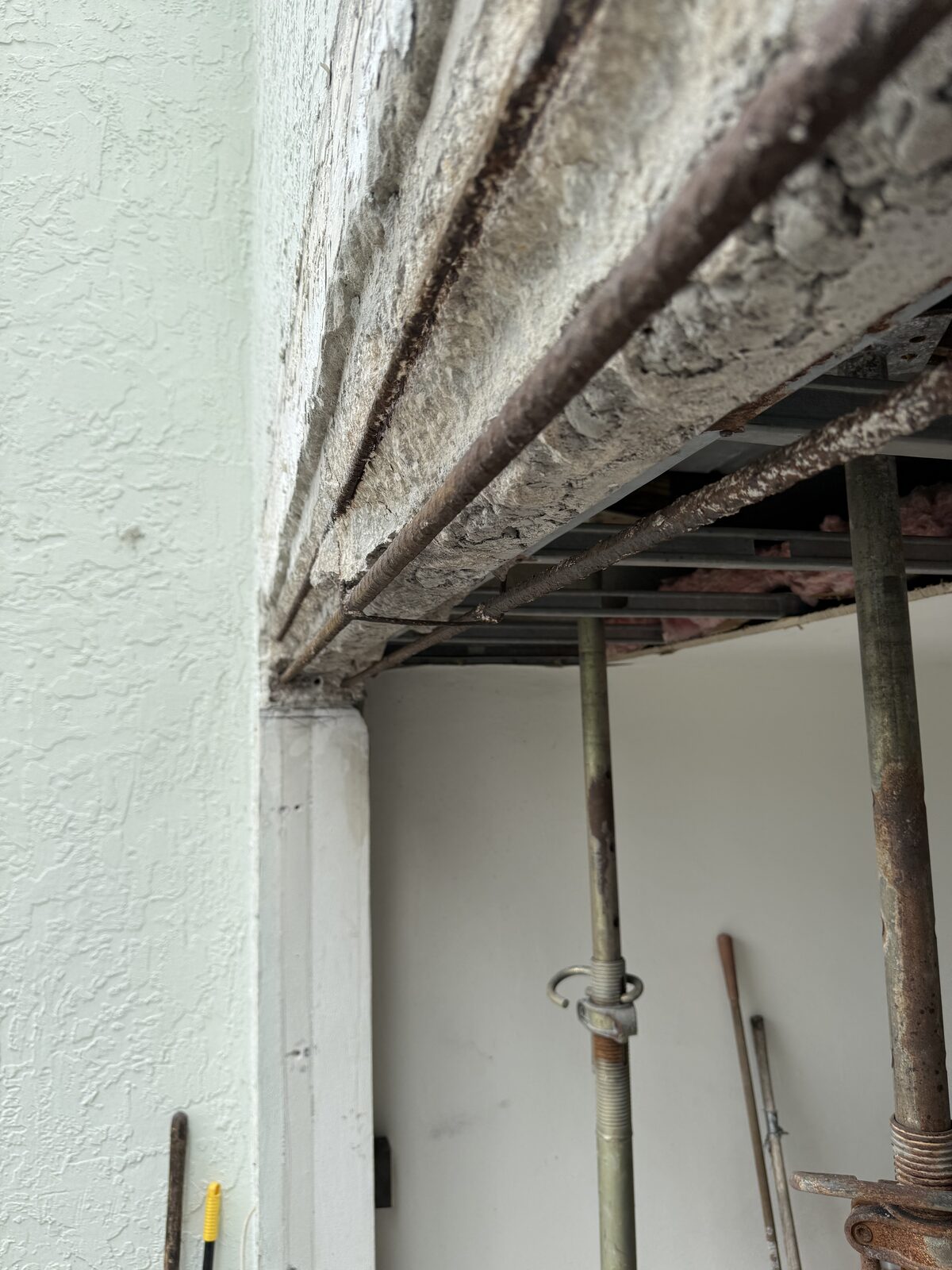 Close-up of a concrete beam cut back to expose two parallel runs of rusted reinforcing bar running the full length of the opening