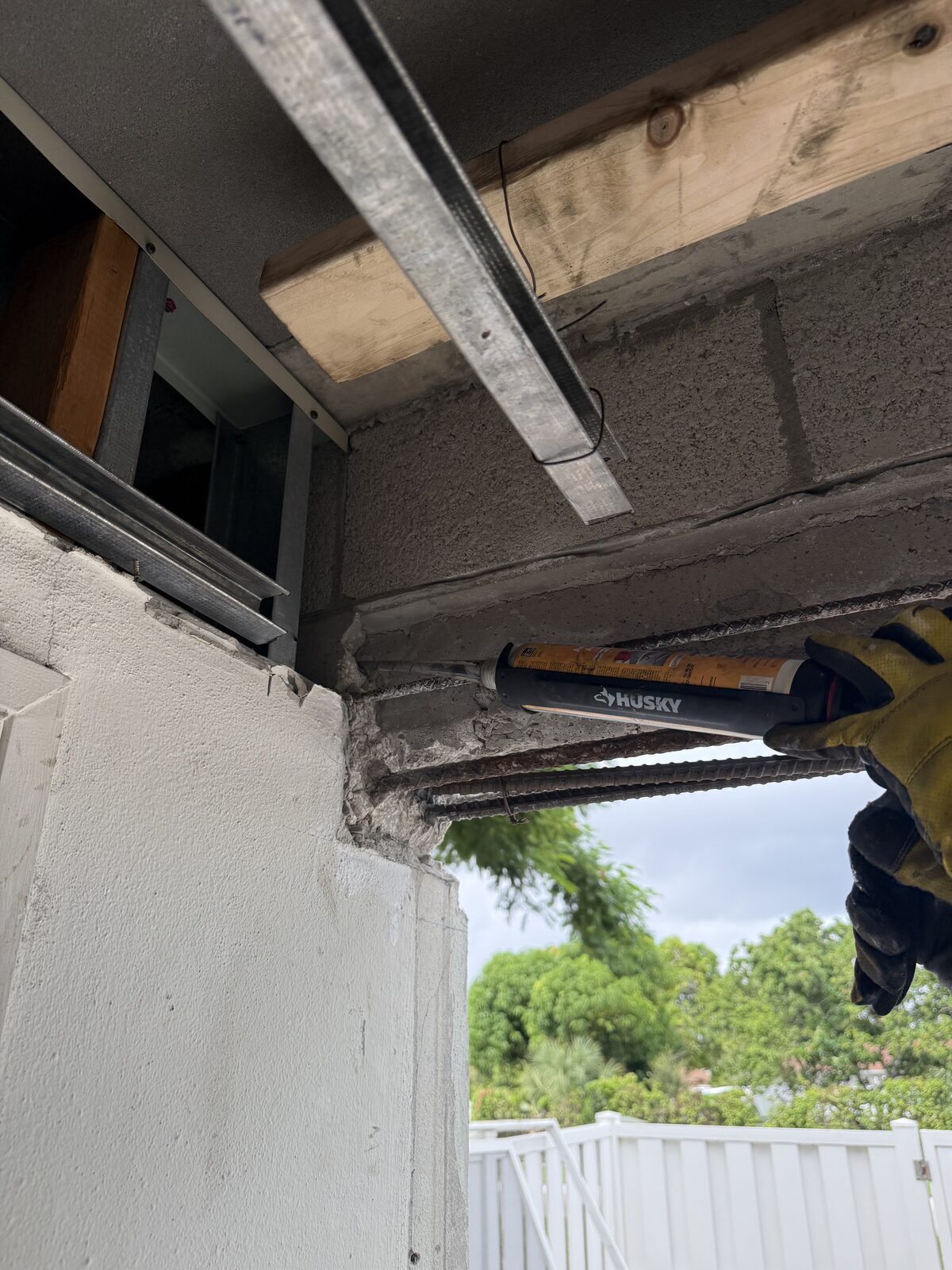 Sealant being applied along the tie-in joint between the rebuilt beam and the existing block wall, shoring timber visible above