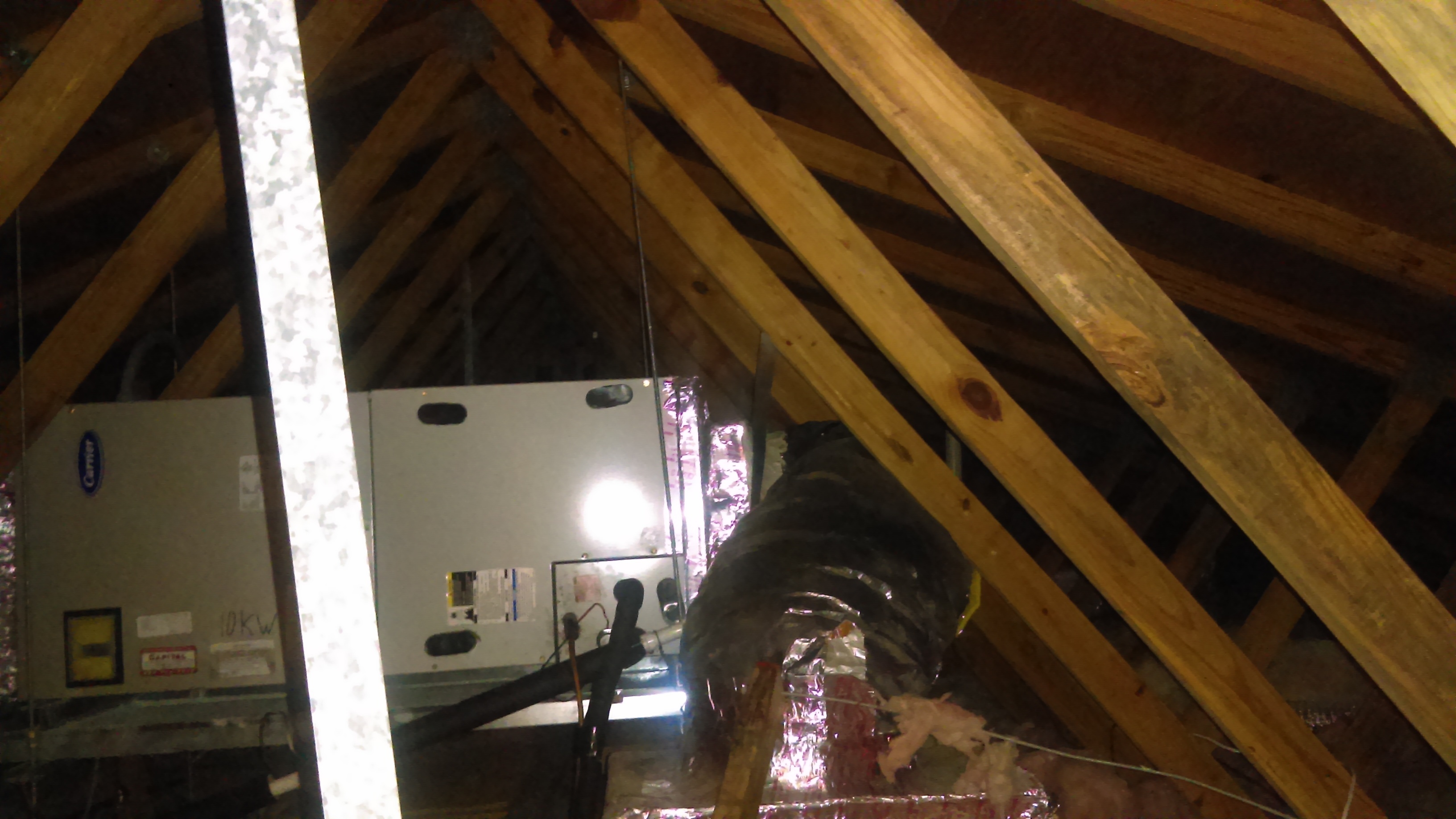 Two Carrier air handlers and insulated flex ductwork sitting in an unconditioned attic between wood roof trusses