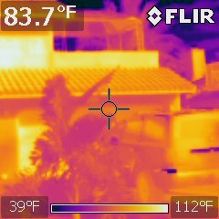 FLIR infrared capture of a roofline beside a tree reading 83.7 degrees Fahrenheit on a 39 to 112 degree scale