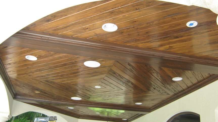 Vaulted reclaimed-wood plank ceiling with recessed lighting over an outdoor loggia — custom carpentry by Bell Engineering & Construction