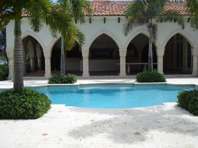 Columned arched loggia beside a curved swimming pool at a waterfront estate