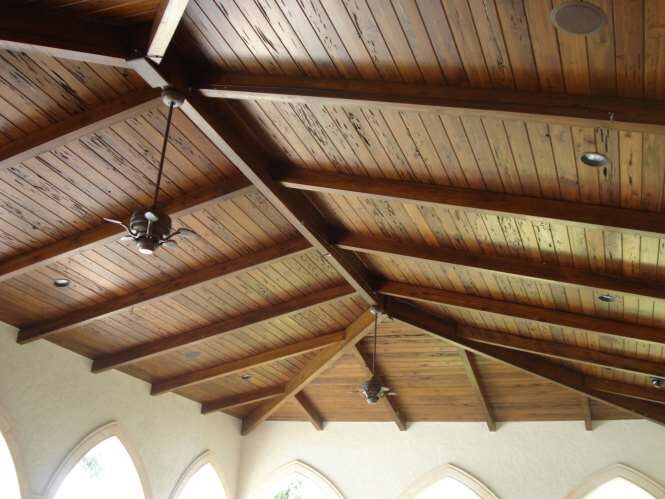 Cathedral great-room ceiling of exposed wood beams and tongue-and-groove planking above arched windows