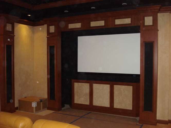 Custom home theater with a projection screen, cherry-wood millwork and acoustic wall panels
