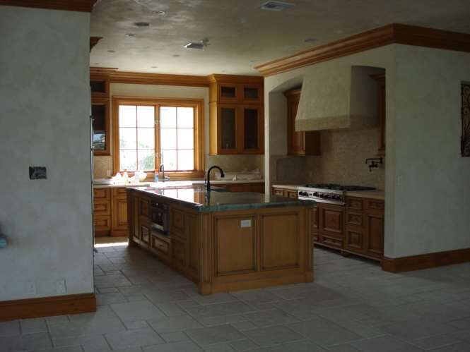 Chef's kitchen with a custom wood island, cast-stone range hood and gas cooktop